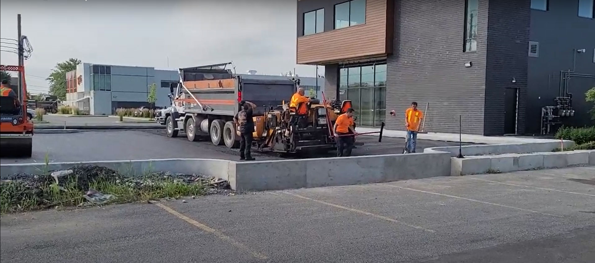 Les entrepreneurs généraux de Protech Construction posent de l'asphalte sur un chantier de construction.