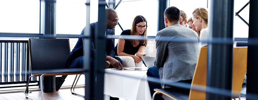 A group of professionals in a meeting, discussing ideas around a table.