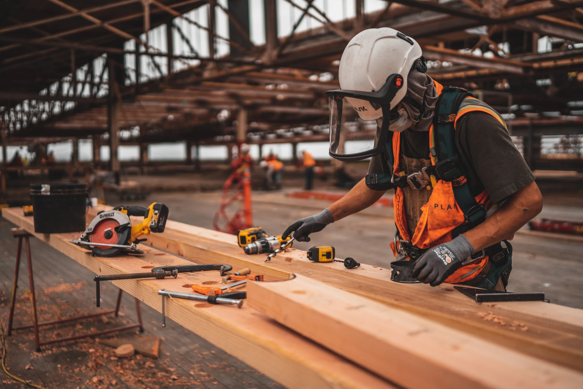 A carpenter cutting wood beams at a construction site.